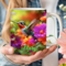 Personalized teacup with hummingbird art. Morning coffee mug with colorful flowers. Close-up of woman holding a personalized hummingbird mug